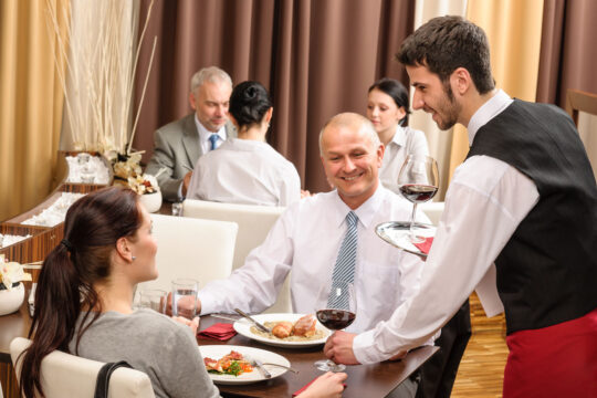 Cameriere sorride alla fidelizzazione dei clienti.