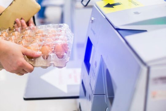 Cliente scansiona una confezione di uova in autonomia con una cassa di self check-out.